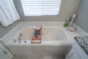 Bathroom with vanity, tiled bath, and tile floors