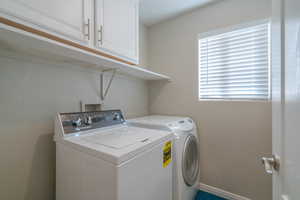 Clothes washing area featuring hookup for a washing machine, washer and dryer, and cabinets