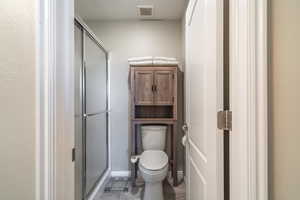 Bathroom with a shower with door, tile floors, and toilet