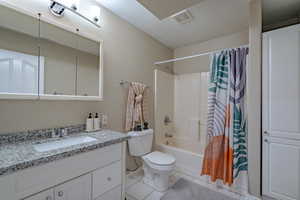 Full bathroom with large vanity, a textured ceiling, toilet, tile floors, and shower / bath combination with curtain