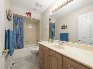 Full bathroom featuring toilet, shower / bath combo with shower curtain, tile floors, and oversized vanity