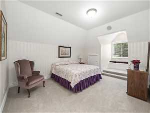 Bedroom with ensuite bathroom lofted ceiling and light carpet