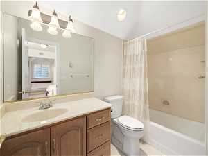 Full ensuite  bathroom with large vanity, tile floors, shower/bathtub combination with curtain, and toilet