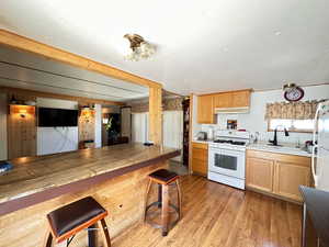 Kitchen with laminate flooring, a breakfast bar area, sink, and white appliances