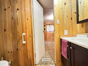 Bathroom with wood walls, vanity, and toilet