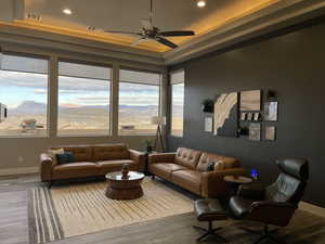 Living room with ceiling fan, a tray ceiling, and wood-type flooring