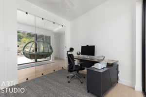 Office space featuring vaulted ceiling and light hardwood / wood-style flooring
