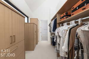 Spacious closet with light colored carpet and lofted ceiling