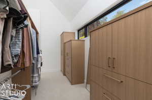 Spacious closet featuring light colored carpet and lofted ceiling