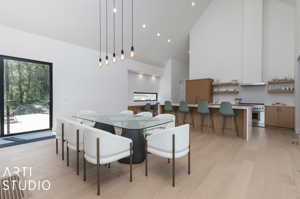 Dining space with plenty of natural light, high vaulted ceiling, and light hardwood / wood-style flooring