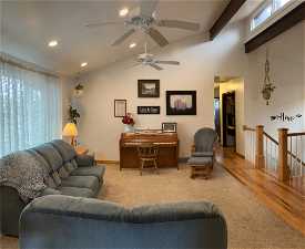 Living room with light hardwood / wood-style floors, ceiling fan, and lofted ceiling with beams