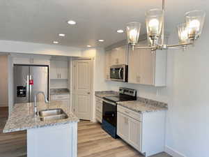 Kitchen with pendant lighting, LVP flooring, sink, and appliances with stainless steel finishes