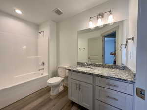 Full bathroom with large vanity, LVP floors, tub / shower combination, and toilet