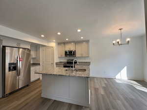Kitchen LVP floors, appliances with stainless steel finishes, decorative light fixtures, and sink