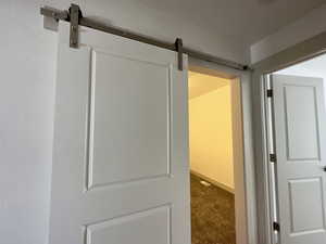 Hallway featuring carpet and a barn door into bonus/game room