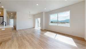 Unfurnished room featuring light hardwood / wood-style floors, a notable chandelier, a water and mountain view, and sink