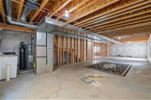 Basement with strapped water heater, heating utilities, and washer / dryer