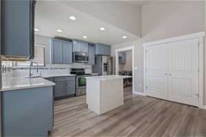 Kitchen featuring appliances with stainless steel finishes, light hardwood / wood-style flooring, washer and clothes dryer, sink, and a center island