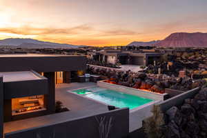 Pool at dusk featuring a mountain view and a patio