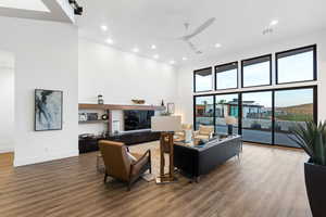 Living room with dark hardwood / wood-style floors, ceiling fan, and a high ceiling