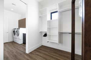 Spacious closet with dark hardwood / wood-style floors and washer and clothes dryer