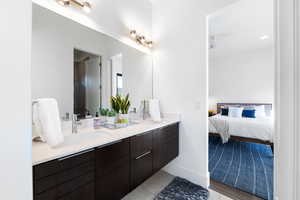 Bathroom with tile flooring, ceiling fan, vanity with extensive cabinet space, and dual sinks