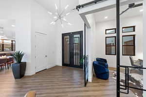 Foyer entrance featuring light hardwood / wood-style flooring, a barn door, a chandelier, and a high ceiling