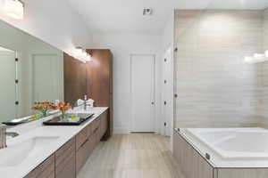 Bathroom featuring a bathtub, dual bowl vanity, and tile flooring