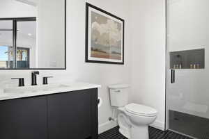 Bathroom featuring an enclosed shower, vanity, tile floors, and toilet