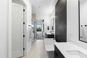 Bathroom with tile walls, tile flooring, vanity, and a tub