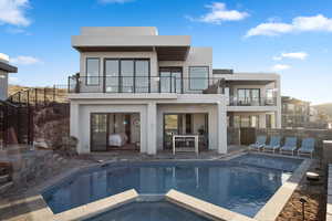 Back of property with a patio, a pool with hot tub, and a balcony