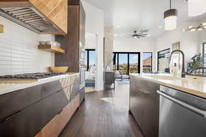 Kitchen featuring appliances with stainless steel finishes, custom exhaust hood, tasteful backsplash, decorative light fixtures, and dark hardwood / wood-style floors