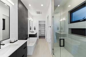 Bathroom with tile walls, independent shower and bath, vanity, and tile floors