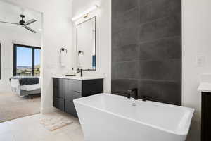 Bathroom featuring tile flooring, oversized vanity, ceiling fan, and a bathtub