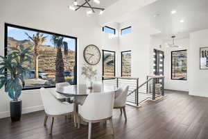 Dining area featuring plenty of natural light, dark hardwood / wood-style flooring, a towering ceiling, and a notable chandelier