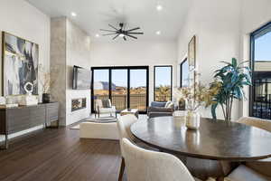 Dining space featuring dark hardwood / wood-style floors, ceiling fan, a tile fireplace, and a towering ceiling