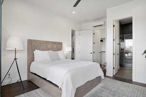 Bedroom with a wall mounted AC, ceiling fan, ensuite bathroom, and dark tile floors