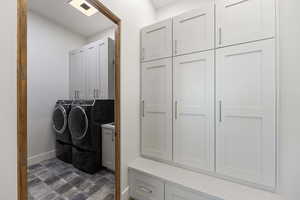 Laundry area with cabinets, dark tile flooring, and washer and clothes dryer