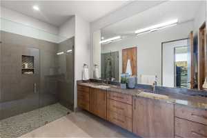 Bathroom featuring a shower with shower door, tile floors, and dual vanity