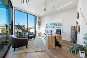 Living room with floor to ceiling windows, light hardwood / wood-style floors, and ceiling fan