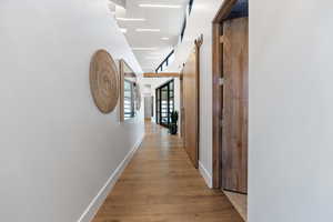 Hallway with a barn door and light wood-type flooring