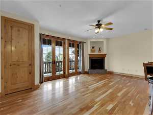 Unfurnished living room with french doors, ceiling fan, and light wood-type flooring