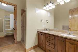 Primary beds bathroom with dual vanity, walk-in shower, walk-in closet, and tile flooring