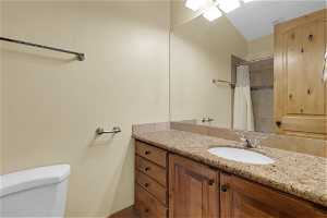 2nd beds bathroom with large vanity, vaulted ceiling, and toilet