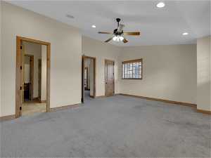 Unfurnished bedroom featuring light colored carpet, connected bathroom, ceiling fan, and lofted ceiling
