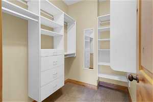 Primary beds spacious walk-in closet featuring light colored carpet