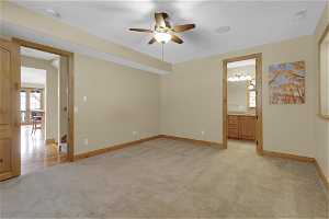 Unfurnished 1st bedroom featuring ceiling fan and light carpet