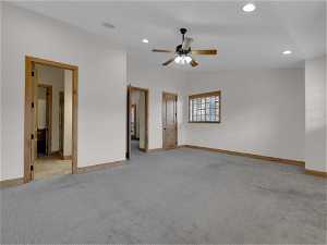 Unfurnished bedroom featuring light colored carpet, lofted ceiling, ceiling fan, and connected bathroom