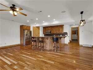 Kitchen with backsplash, ceiling fan, stainless steel appliances, and light hardwood / wood-style floors