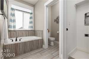 Bathroom with tile flooring, a relaxing tiled bath, a healthy amount of sunlight